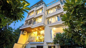 Un immeuble à plusieurs étages, doté de balcons et de grandes fenêtres, entouré d’une végétation luxuriante.