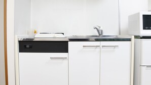Une petite cuisine équipée d’un lave-vaisselle, d’un évier doté d’un robinet moderne et d’un four à micro-ondes.