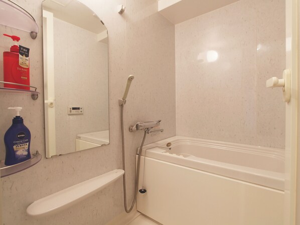 Un baño con bañera, ducha, inodoro y espejo.