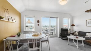 Un vaste espace de vie comprenant un balcon, une table à manger et un canapé.