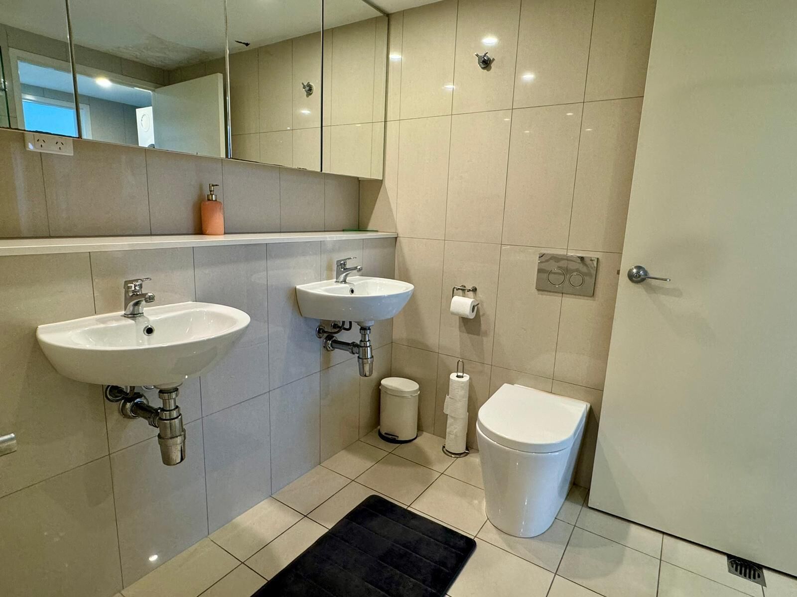 A modern bathroom with two sinks, a toilet, and a bidet.