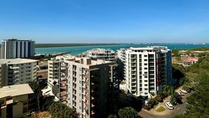 A high-rise residential building with multiple balconies, a marina in the background, and a clear blue sky. - Katara on Woods (Darwin)