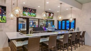 A modern kitchen with a large island, bar seating, and sports-themed decor.