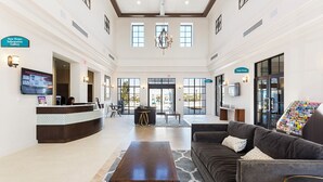 A spacious lobby with a reception desk, seating area, and a Game Room sign.