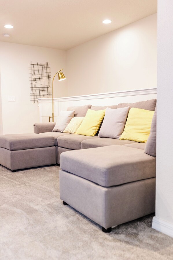 Ein modernes Wohnzimmer mit einem Ecksofa, einer Stehlampe und einem Wandbild.
