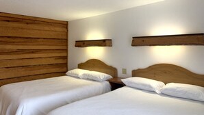 Une chambre avec deux lits simples, des têtes de lit en bois et un panneau mural en bois.