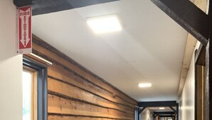 Un couloir avec des lambris en bois, un panneau indiquant la sortie de secours et un sol carrelé.
