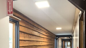 Un couloir avec un lambris en bois d’un côté, un sol carrelé et un panneau indiquant la sortie de secours.