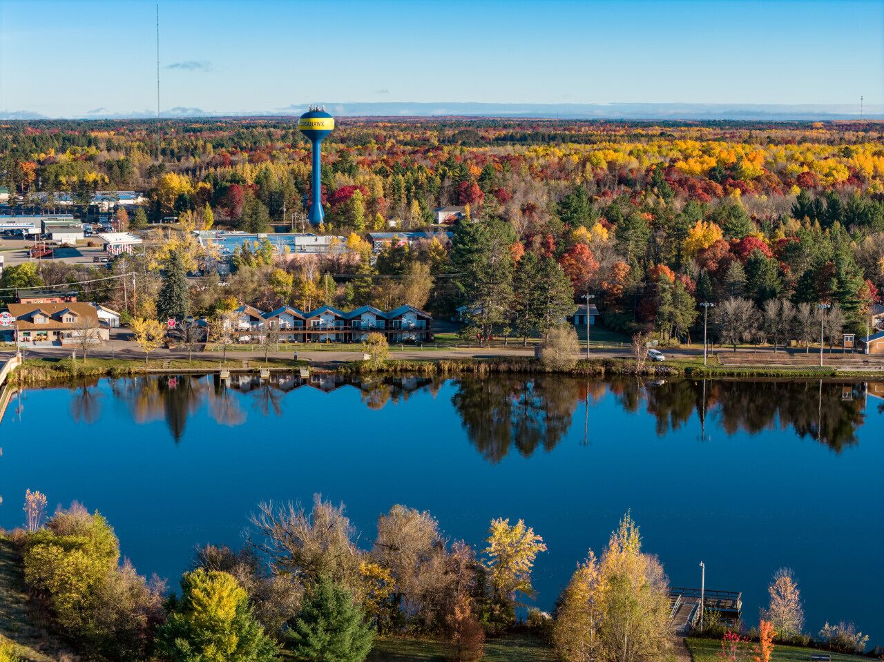 A lake with a water tower and houses in the background.