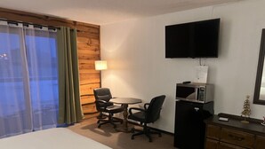 Une chambre d’hôtel avec un lit, un bureau avec un ordinateur, une télévision et un petit sapin de Noël.