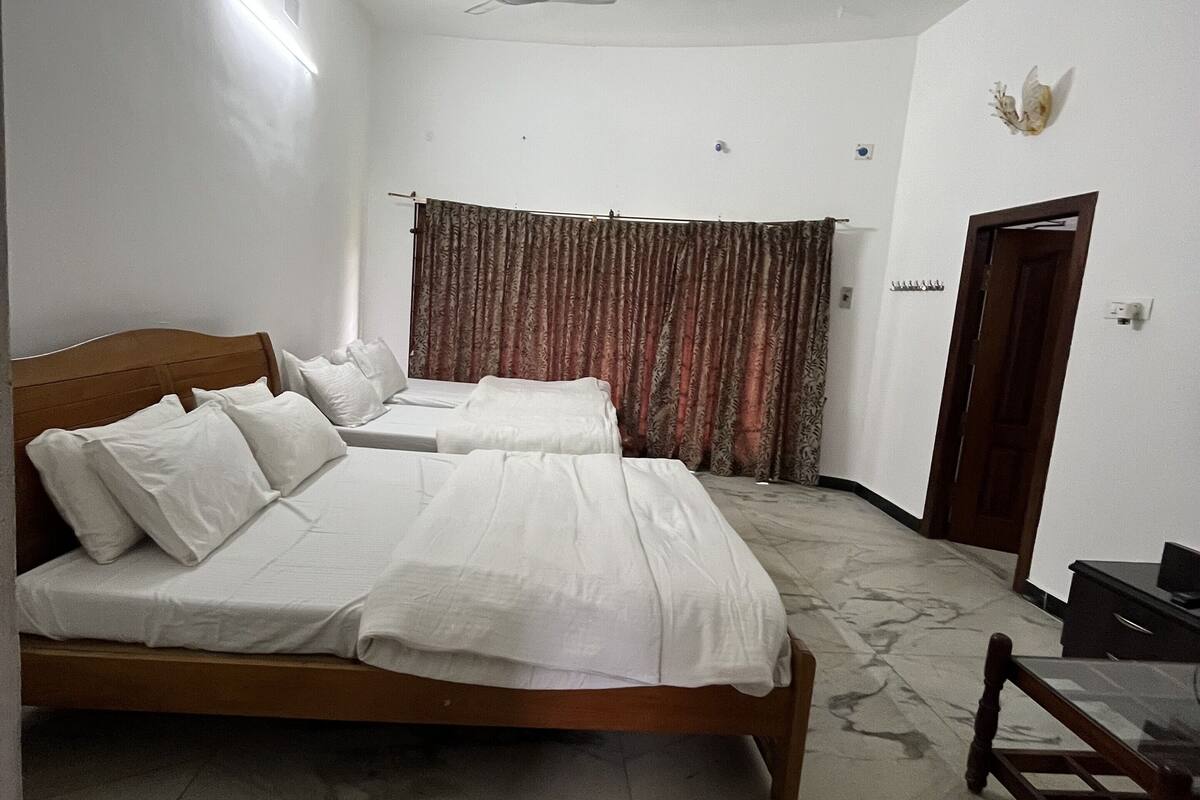 A hotel room with two beds, a ceiling fan, a wooden chair, and a desk.