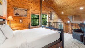 A wooden cabin bedroom with a bed, a chair, a ceiling fan, and a window. - 2BD + Loft, Walk-In Cabin- Discounts on Golf & Tickets! (Branson)