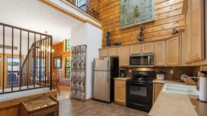 A spacious kitchen with wooden cabinets, a stainless steel refrigerator, a microwave, an oven, and a sink. - 2BD + Loft, Walk-In Cabin- Discounts on Golf & Tickets! (Branson)