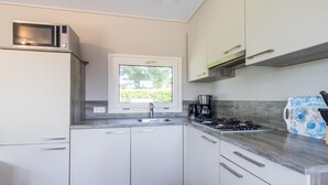 Eine moderne Küche mit weißen Schränken, einem Fenster, einer Mikrowelle, einer Kaffeemaschine und einem Gaskochfeld.