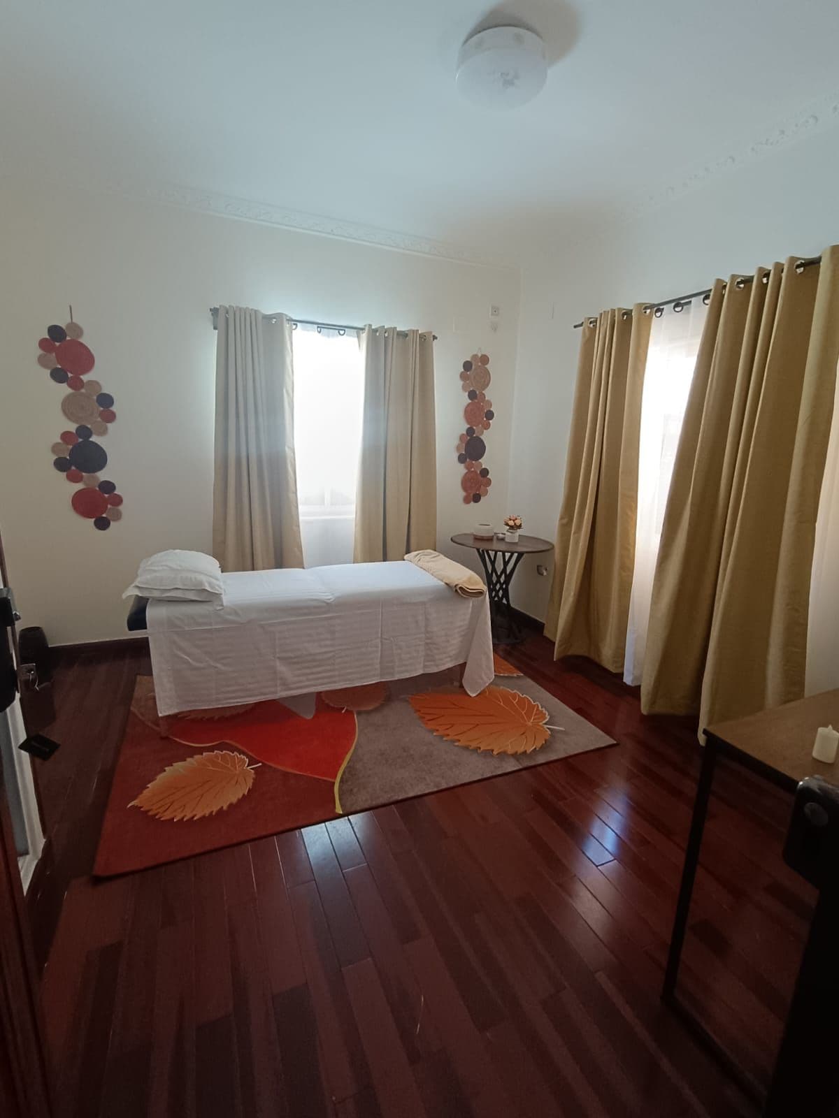 Un dormitorio con una cama, una mesita pequeña y cortinas.