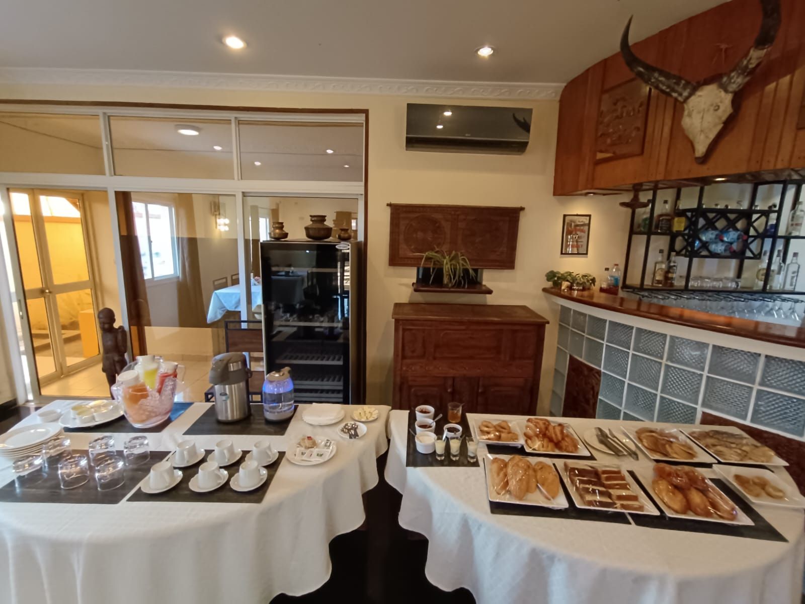 A dining area with a buffet setup, a refrigerator, and a bar area with a decorative skull.