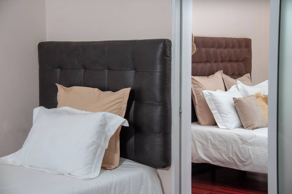Two beds with different headboard designs, one with a black headboard and the other with a brown headboard.