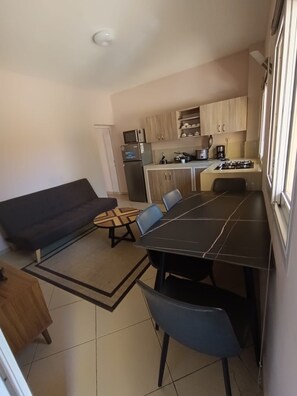 A compact living space with a dining area, kitchenette, and a sofa. - Hôtel Les 12 Collines, Ivato Ambohijanahary (Antananarivo)