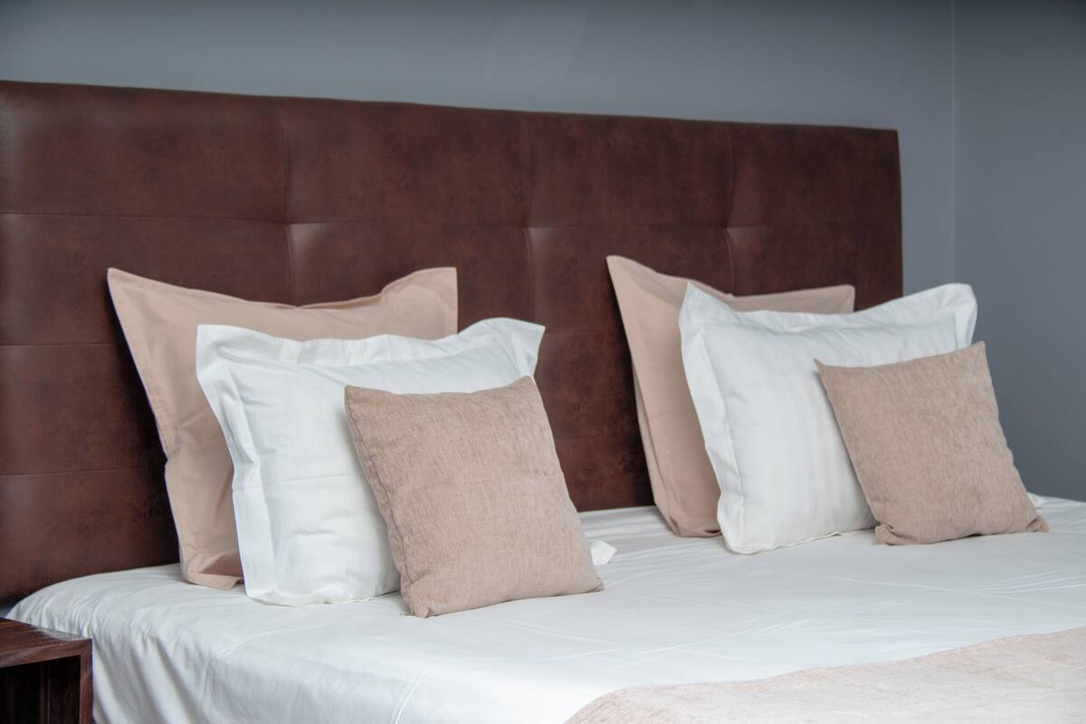 A bed with a headboard, multiple pillows, and a white bedspread.