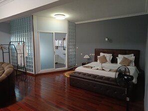 A hotel room with a bed, bedside table, lamp, and a fan.