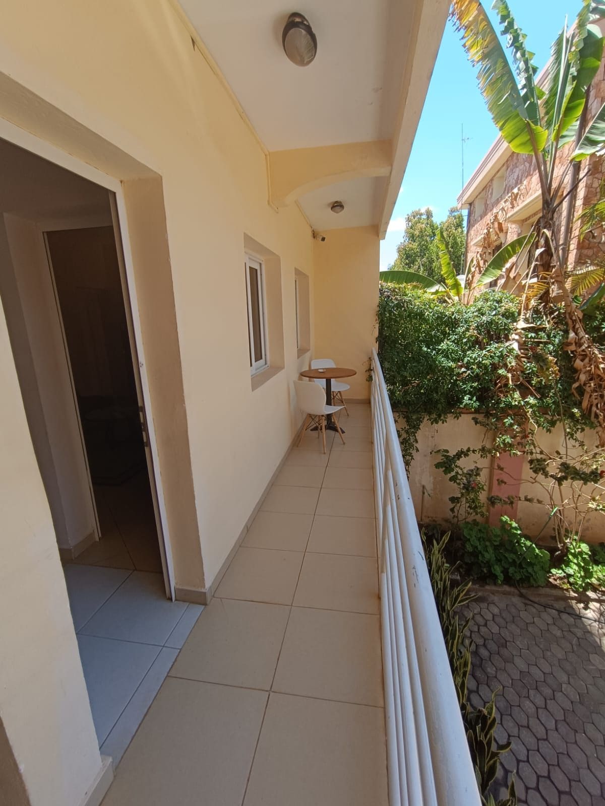 A balcony with a tiled floor, a small table with chairs, and a door leading to an interior space.