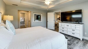 Ein Schlafzimmer mit einem großen Bett, einem Deckenventilator, einem Fernseher und einer Kommode.