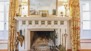 Una chimenea con un espejo encima, flanqueada por cortinas y apliques de pared.