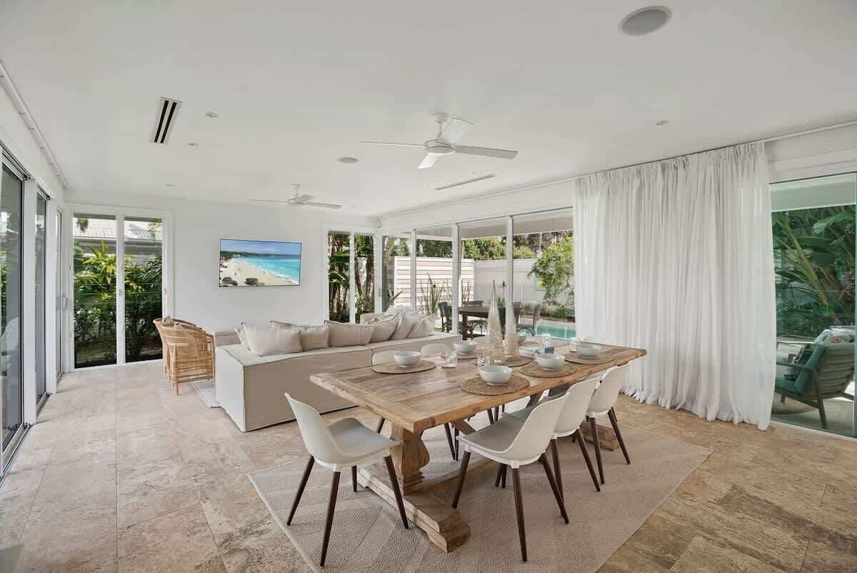 A modern dining area with a wooden table, white chairs, and a glass partition.