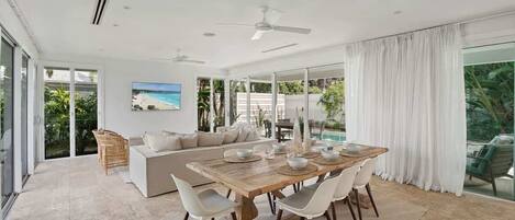 A modern dining area with a wooden table, white chairs, and a glass partition.