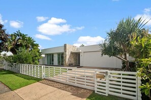 A modern two-story house with a white exterior, a stone accent wall, and a white fence. - Casa Luxe (Kingscliff)