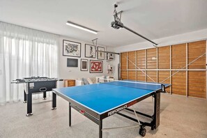 A room with a foosball table, a ping pong table, and a ceiling-mounted projector. - Casa Luxe (Kingscliff)