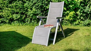 A single chair with a mesh backrest and armrests, placed on a grassy lawn with a hedge in the background. - Apartment 'Ferienwohnung Lisa' with Private Terrace, Private Garden and Wi-Fi (Behrensdorf)