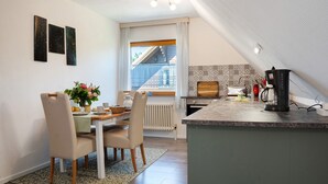 A modern kitchen with a dining area, a coffee maker, and a view of a building outside. - Apartment 'Ferienwohnung Lisa' with Private Terrace, Private Garden and Wi-Fi (Behrensdorf)