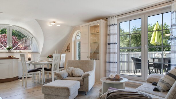Ein modernes Interieur mit Essbereich, einer Sofagarnitur und Blick durch große Fenster.