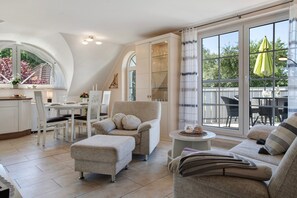 A modern interior with a dining area, a sofa set, and a view through large windows. - Apartment 'Ferienwohnung Abendsonne' with Balcony and Wi-Fi (Zingst)