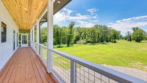 Una terraza cubierta de madera con vista a un campo verde y árboles.