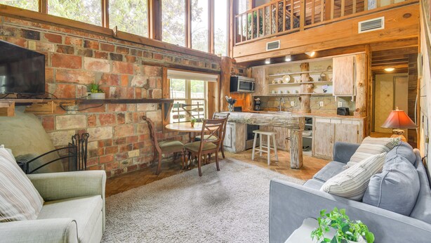 A rustic cabin interior with a dining area, kitchen, and seating space. - Riverfront Deck: Outdoor Retreat in Fairhope! (Fairhope)