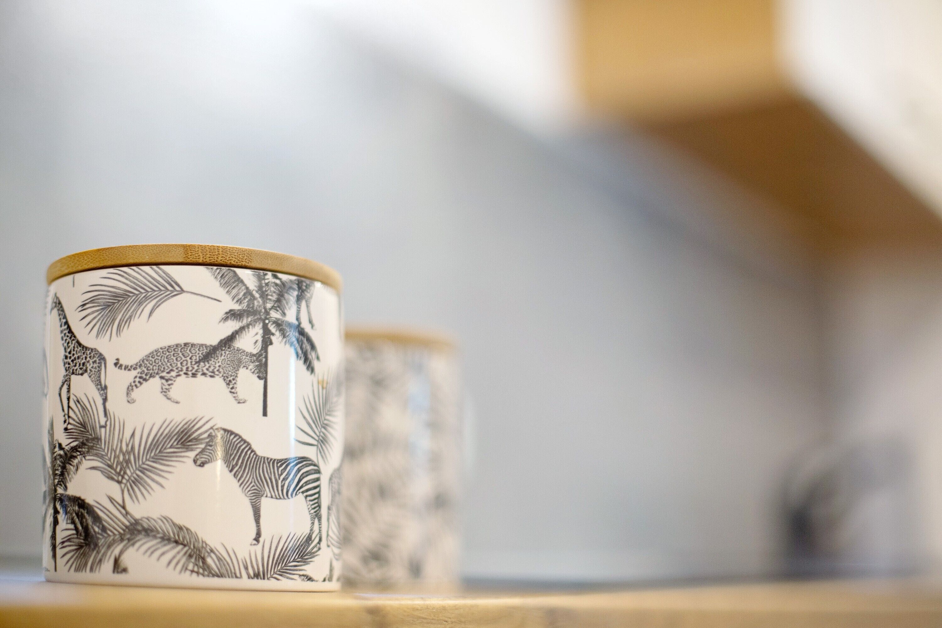 A close-up of a decorative mug with a giraffe and zebra pattern, placed on a wooden surface.