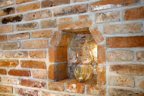 Paredes de tijolo com um pequeno nicho contendo duas taças de vinho e um vaso decorativo.