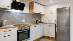 A modern kitchen with white cabinets, a stainless steel refrigerator, a built-in oven, and a wooden countertop. - Apartment 'Felicitas' with Wi-Fi (Tann)