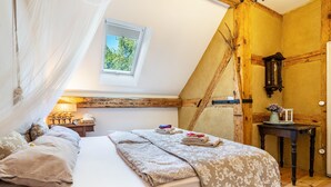 Un dormitorio con cama, ventana, mesita de noche y un reloj de pared.