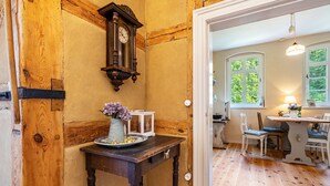Un interior de madera con una mesa, sillas, un reloj y una ventana.