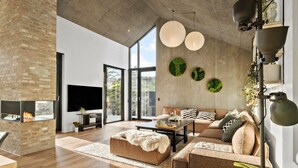 A spacious living room with a fireplace, a large TV, a sofa, and a coffee table. - 4 bedroom pet friendly home in Blokhus (Blokhus)