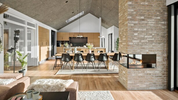 A spacious living area with a high ceiling, a fireplace, and a modern kitchen in the background. - 4 bedroom pet friendly home in Blokhus (Blokhus)