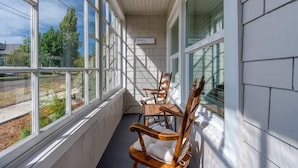 A covered porch with large windows and wooden chairs. - #StayinMyDistrict Historic Heritage Walk to Bay (Coos Bay)