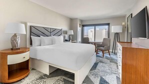 Une chambre d’hôtel avec un grand lit, des tables de chevet, un bureau et une chaise.