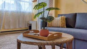 Una sala de estar con un sofá, una planta en maceta, una bandeja y una lámpara.