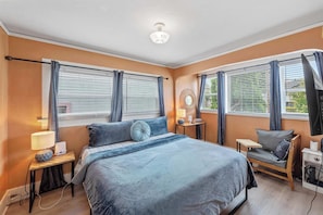 A bedroom with a bed, bedside tables, a chair, a lamp, and a ceiling fan. - #StayinMyDistrict Historic Heritage House Apt (Coos Bay)