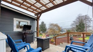 An outdoor patio with a grill, a fire pit, and blue chairs.