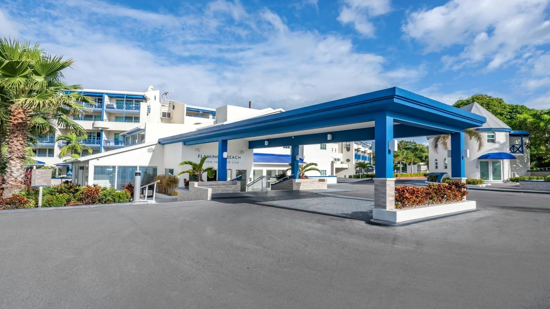 A modern hotel with a blue and white color scheme, featuring a covered outdoor area with a staircase leading to the entrance.